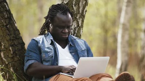 New normal. Remote work concept. African man using laptop in the nature Stock Photos