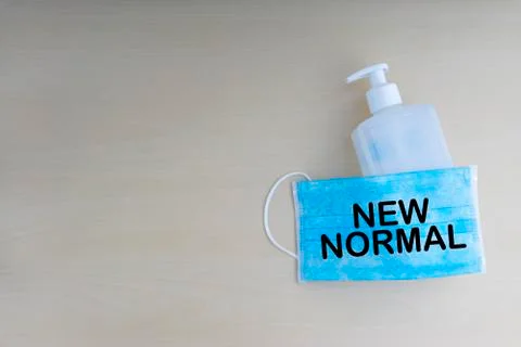 NEW NORMAL text with face mask and hand sanitizer on wooden background Stock Photos