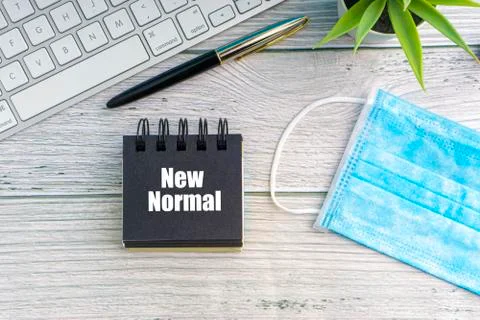 NEW NORMAL text with notepad, safety face mask, keyboard, fountain pen and de 库存照片