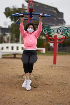 New normal. woman does push-ups with machine in the park. woman with mask or  스톡 사진