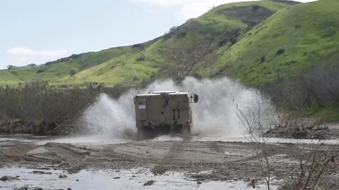New Oshkosh joint light tactical vehicle being test driven through muddy water Stock Footage 104601133