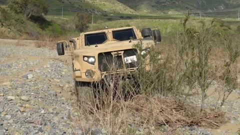 New Oshkosh joint light tactical vehicle being test driven over uneven terrain Stock Footage 104601223