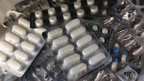New packages of white transparent oval tablets fall into a pile. Real time, medi Stock Footage 145586914