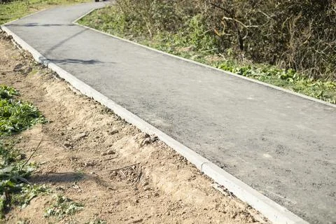 New path in the park. Asphalt path. Empty path. Thin borders. Stock Photos