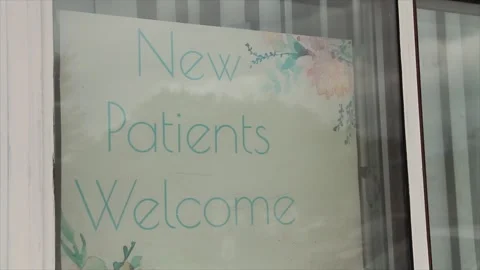 New patients welcome writing caption text sign inside window with traffic seen Stock Footage 247142889