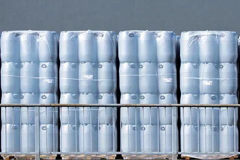 New plastic drums stacked on pallets at warehouse, industrial storage Stock Photos