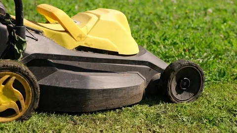 A new powerful lawn mower is moving on green grass. Black and yellow lawn mower Stock Footage 313108948