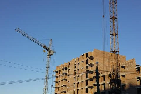 New residential complex construction site with cranes and brick facade. Stock Photos
