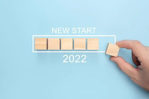 New start 2022 concept. Loading new year 2022 with hand putting wood cube in  Stock Photos