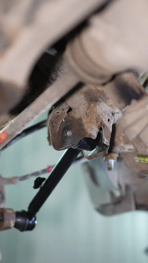 A new suspension control arm aligned inside a rusty underbody bracket. Stock Footage 345909770