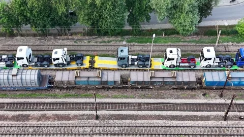 New trucks being transported on railway platforms, continuous flow of vehicles Видео 341398464