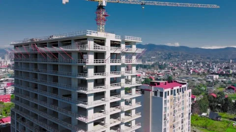 New unfinished tall apartment complex against blue sky, mountains, sea Stock Footage 239254486
