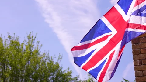 New Union Jack gently flutters around a corner Video stock 240477344