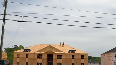 New urban apartment home complex being built slow motion men walking on roof Stock Footage 180237632