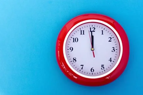 New year concept - Red wall clock pointing at 12 o'clock on blue background Stock Photos