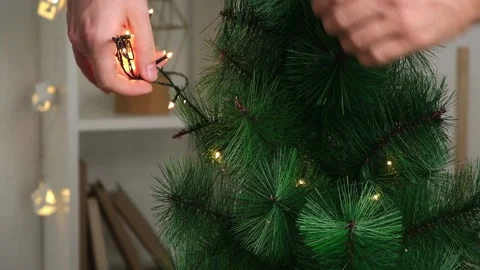 New Year decor. A man decorates a Christmas tree with an electric garland Stock Footage 212790190