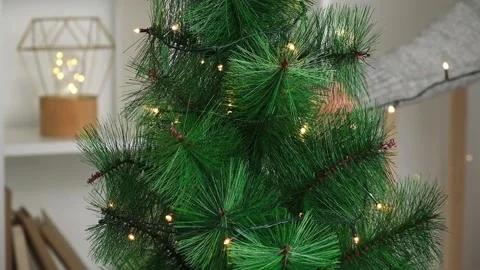 New Year decor. A man decorates a Christmas tree with an electric garland Stock Footage 213704111
