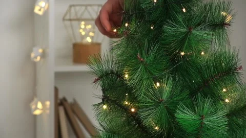 New Year decor. A man decorates a Christmas tree with an electric garland Stock Footage 219751672