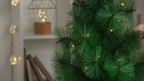 New Year decor. A man decorates a Christmas tree with an electric garland Stock Footage 220099949
