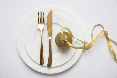 New year dinner table setting, Gold xmas ball with ribbon and cutlery on whit Stock Photos