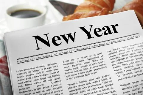 New Year in newspaper layout on a breakfast table with a blurry cup of coff.. Stock Photos