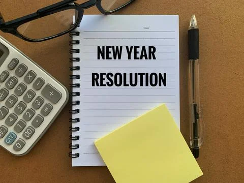 New year resolution text on note pad with pen, glass, calculator and brown table Stock Photos