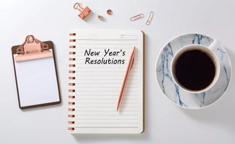 New year resolutions in notebook with rose gold pen, clipboard and coffee cup Stock Photos
