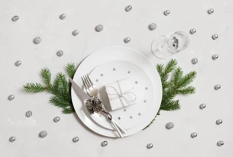 New Year table setting with gift in plates and silver decor on white Stock Photos
