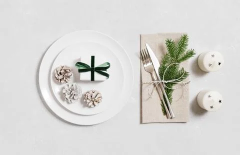 New Year table setting with gifts, fir branches, candles and cones on a white Stock Photos