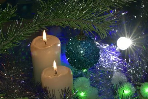 New Year's atmosphere, burning candles, colored Christmas tree garlands. A gr Stock Photos