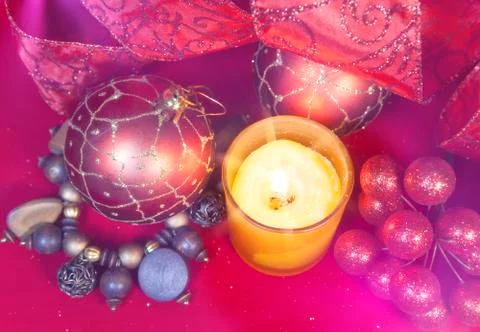 New Year's composition on a red background - ball and ribbon and a candle Foto stock