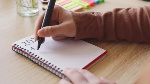 New year's resolutions. Hand starting 2024 goals indexed list in notebook Stock Footage 256609795