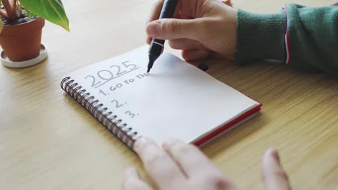 New year's resolutions. Hand starting 2025 goals indexed list in notebook Stock Footage 290237383