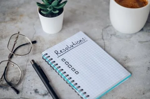 New Years Resolutions written in a notebook with plans for future goals and.. Stock Photos