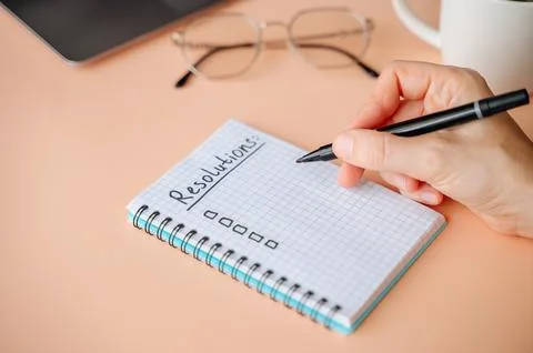 New Years Resolutions written in a notebook with plans for future goals and.. Stock Photos