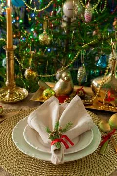 New Year's table setting in gold color, against the background of a decorated Stock Photos