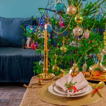 New Year's table setting in gold color, against the background of a decorated Stock Photos