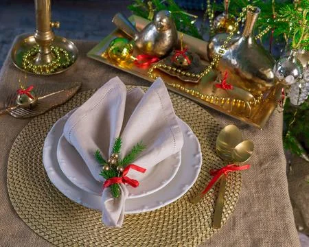New Year's table setting in gold color, against the background of a decorated Stock Photos