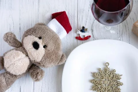 New Year's table setting. Toy bear in Santa's hat, snowflake, plate and glass Stock Photos