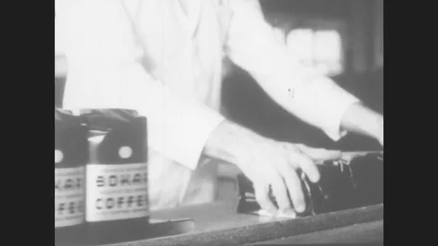 New York, 1930s: Man pulls rows of packaged coffee into bag. Man at conveyor Stock Footage 78549733