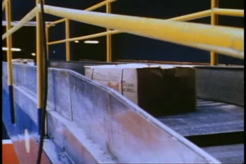 NEW YORK, 1982, QE2 loading the ship's hold, cartons on conveyor belt Stock Footage