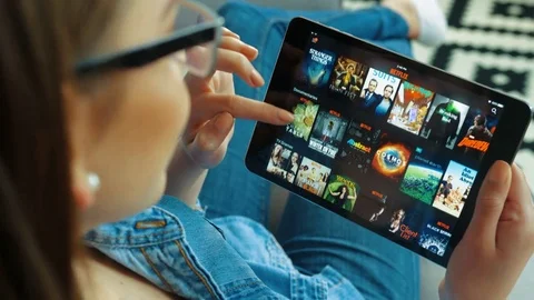 New York - May 15, 2017: Young woman using Netflix app on black tablet device Stock Footage 76454014