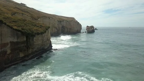New Zealand - Waves Crashing into Rugged Cliff Face Aerial Stock Footage
