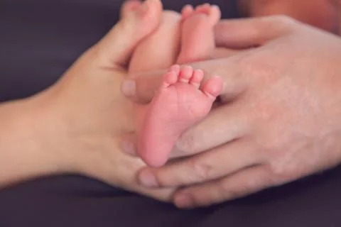 Newborn babies feet with parents hands in a heart shape Stock Photos