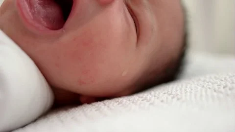 Newborn baby crying in cot. A single tear on her cheek. 库存影片 83792812