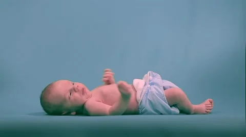 Newborn baby lying and pulling the handles on the background. Video stock 50241753