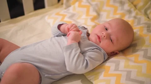 Newborn baby smiling while lying on his crib at home Stock Footage 124642627