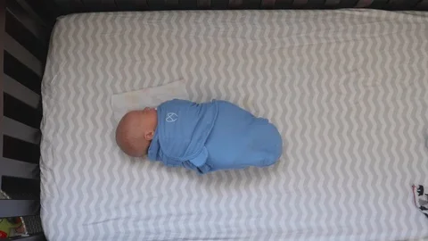 Newborn Baby Swaddled in Sleeping in the Crib