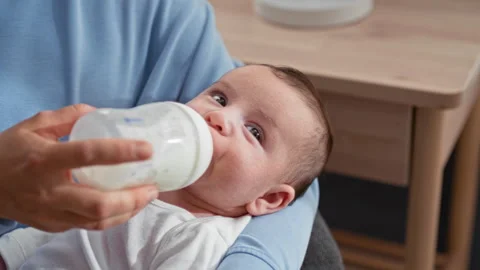 Newborn boy bottle feeding with face and eyes visible, hand holding the bot.. Stock Footage 339169265