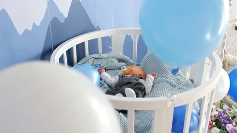 Newborn boy crying lying in a bed among air balloons Stock Footage 116278840